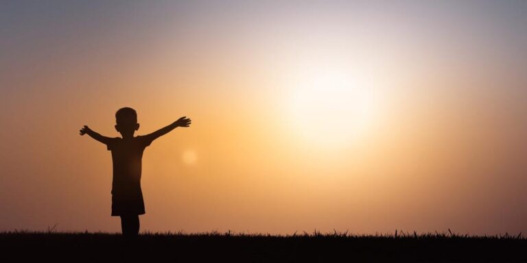 little_boy_with_arms_raised_in_sun